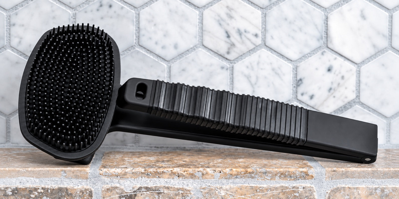 Black Bearback scrubber with its handle folded for close-in use on a shower shelf