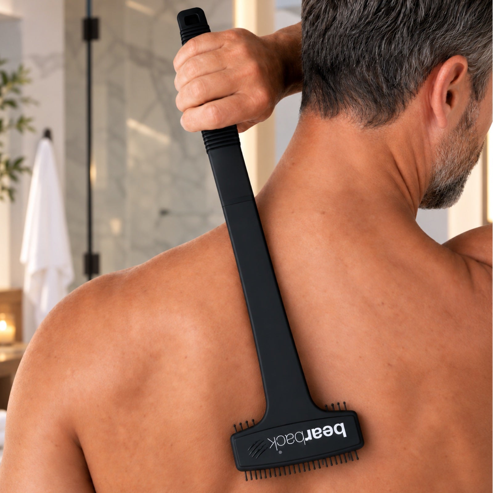 A man reaching his back with an extended Bearback scratcher